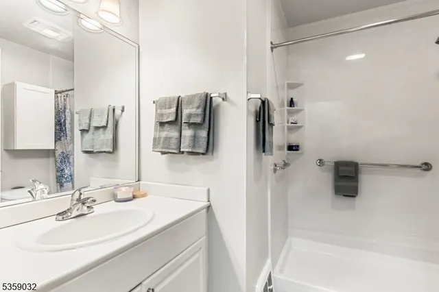 a bathroom with a sink vanity granite tub shower and mirror