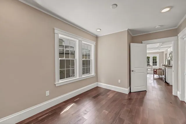 a view of empty room with wooden floor and a window
