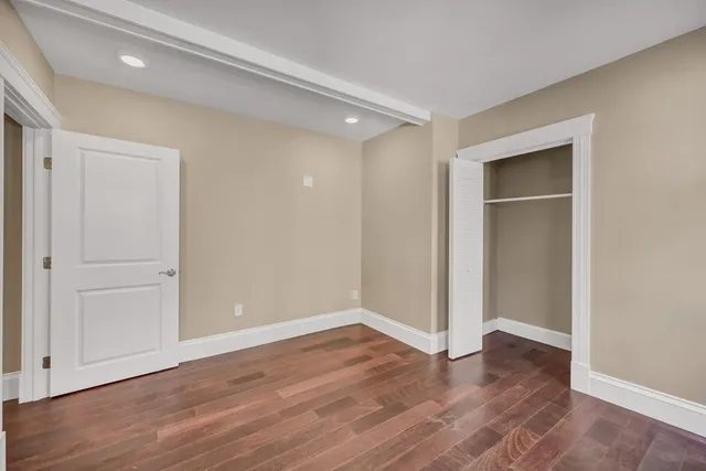an empty room with wooden floor & closet area