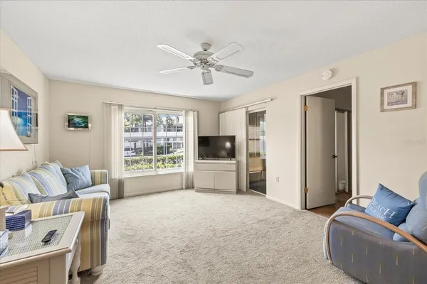 a living room with furniture a flat screen tv and a large window