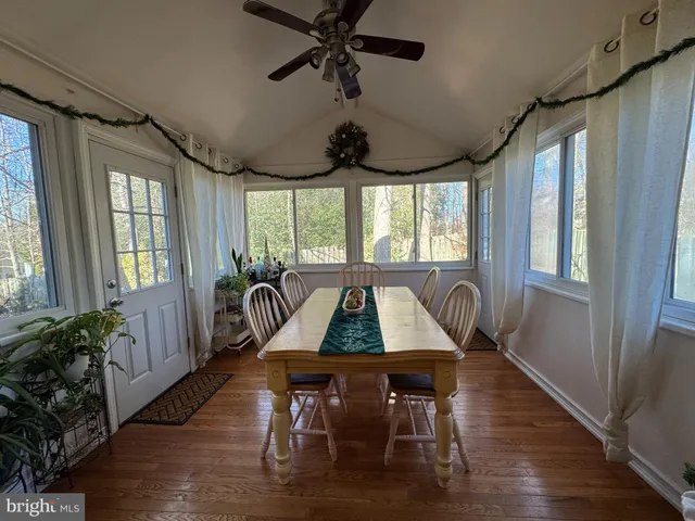 a dining room with wooden floor a chandelier a wooden table and chairs