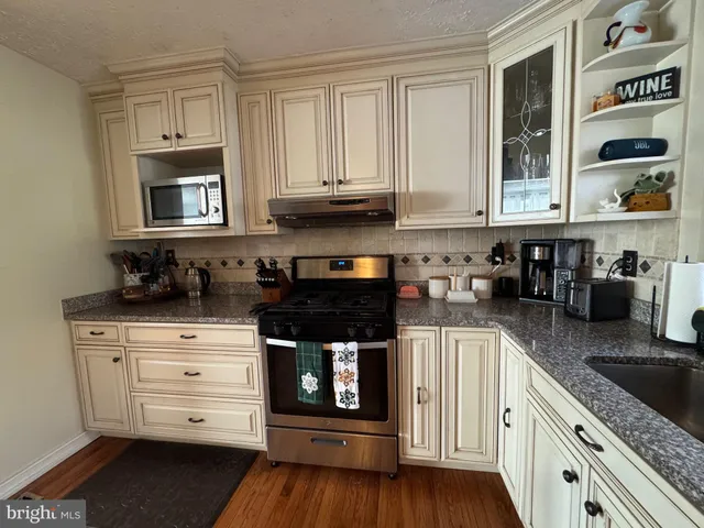 a kitchen with stainless steel appliances granite countertop a stove and cabinets