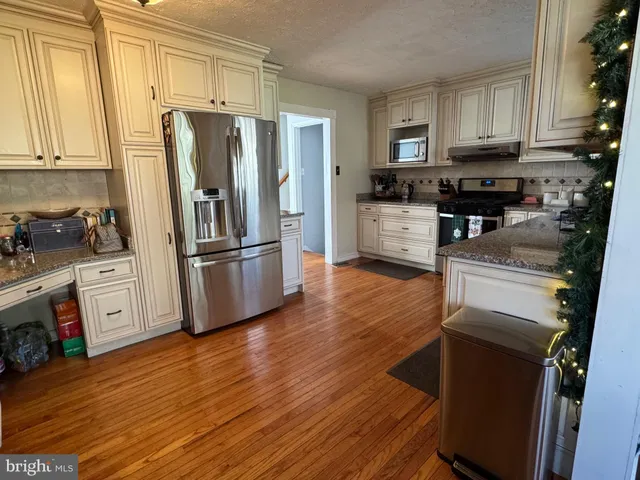 a kitchen with granite countertop wooden floors stainless steel appliances and cabinets