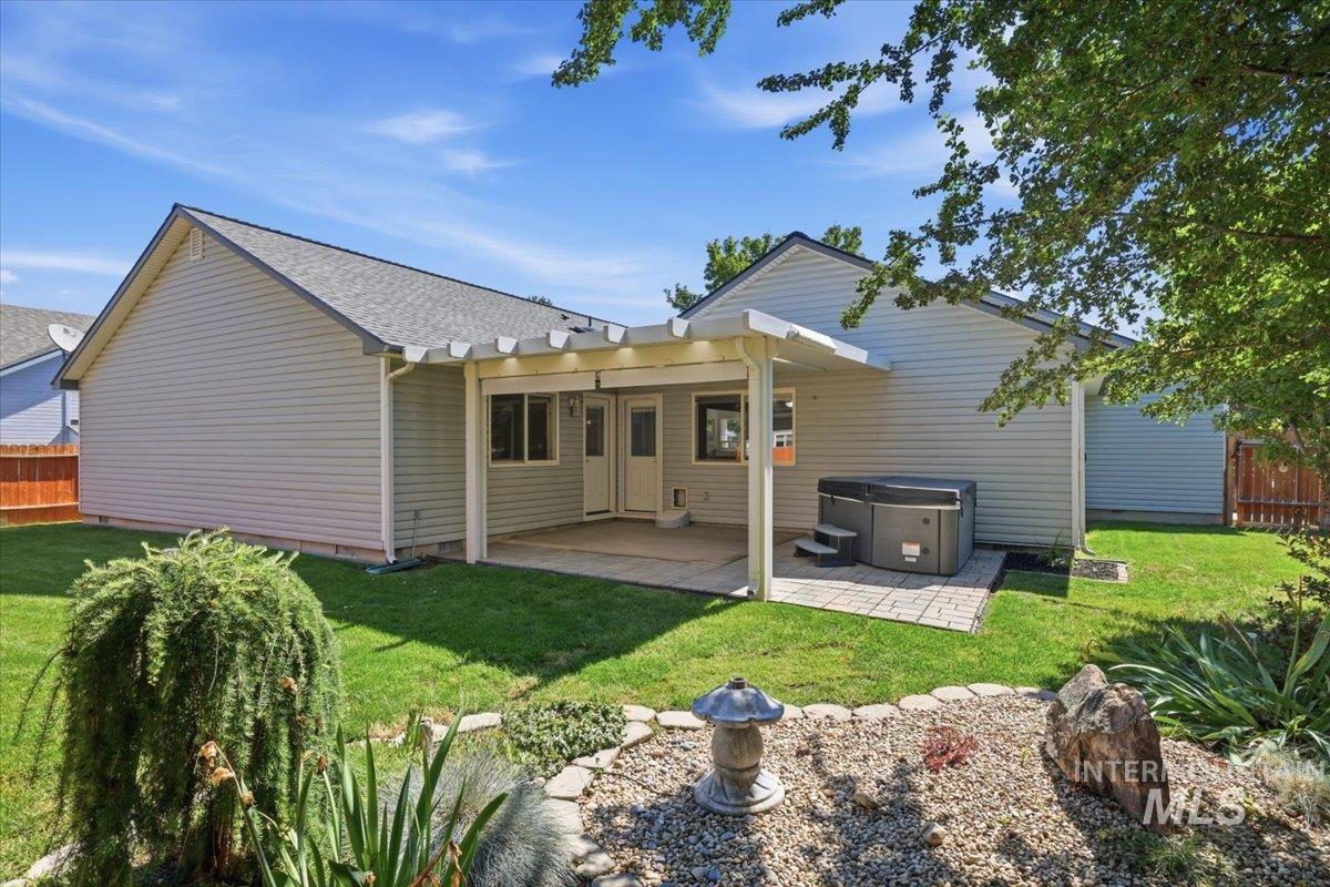 2075 North Springland Place Boise, ID 83713 - Photo 40 of 49 Expansive backyard featuring a covered patio, a hot tub on a paver base, a manicured lawn, and mature trees