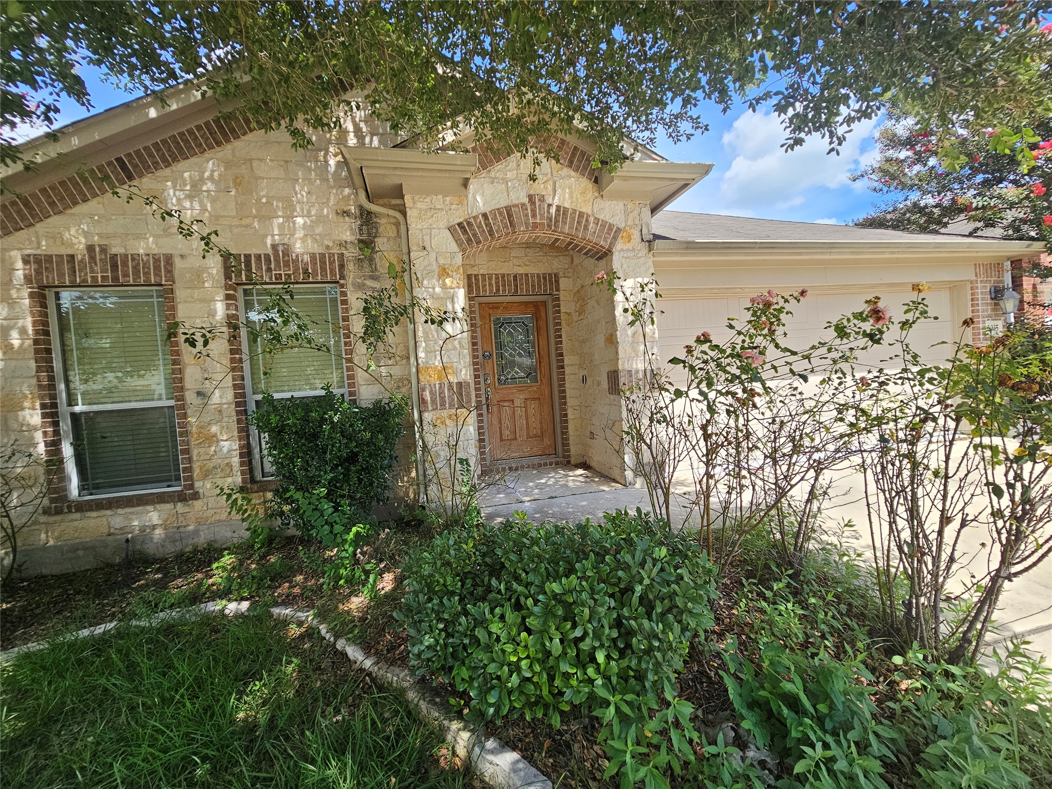 2035 Intrepid Drive Buda, TX 78610 - Photo 1 of 26 A charming single-story home with a stone and brick facade and lush front yard landscaping.