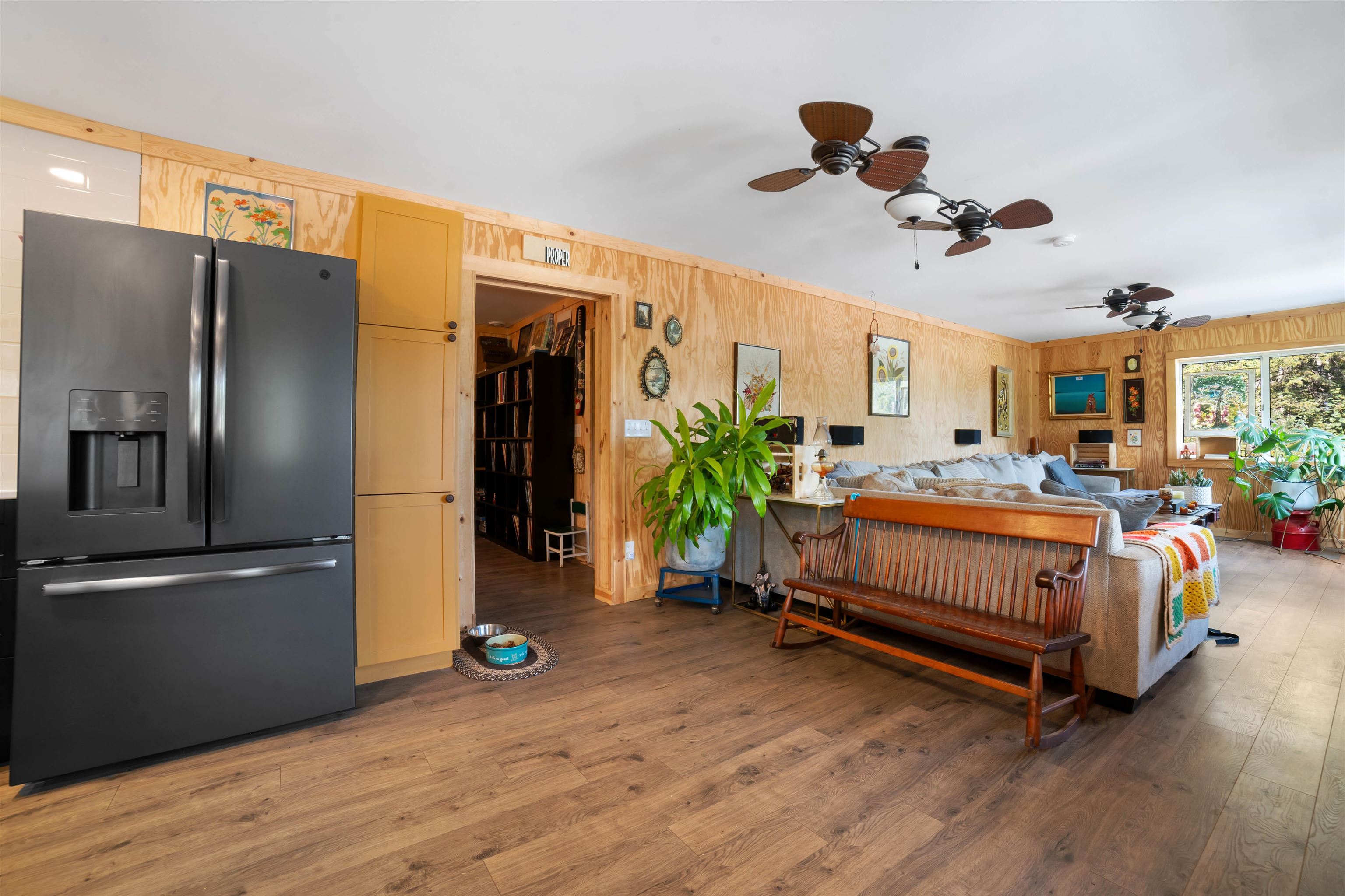 1159 East County Rd B Foxboro, WI 54836 - Photo 16 of 29 Bedroom with wood-type flooring, wooden walls, stainless steel fridge with ice dispenser, and ceiling fan