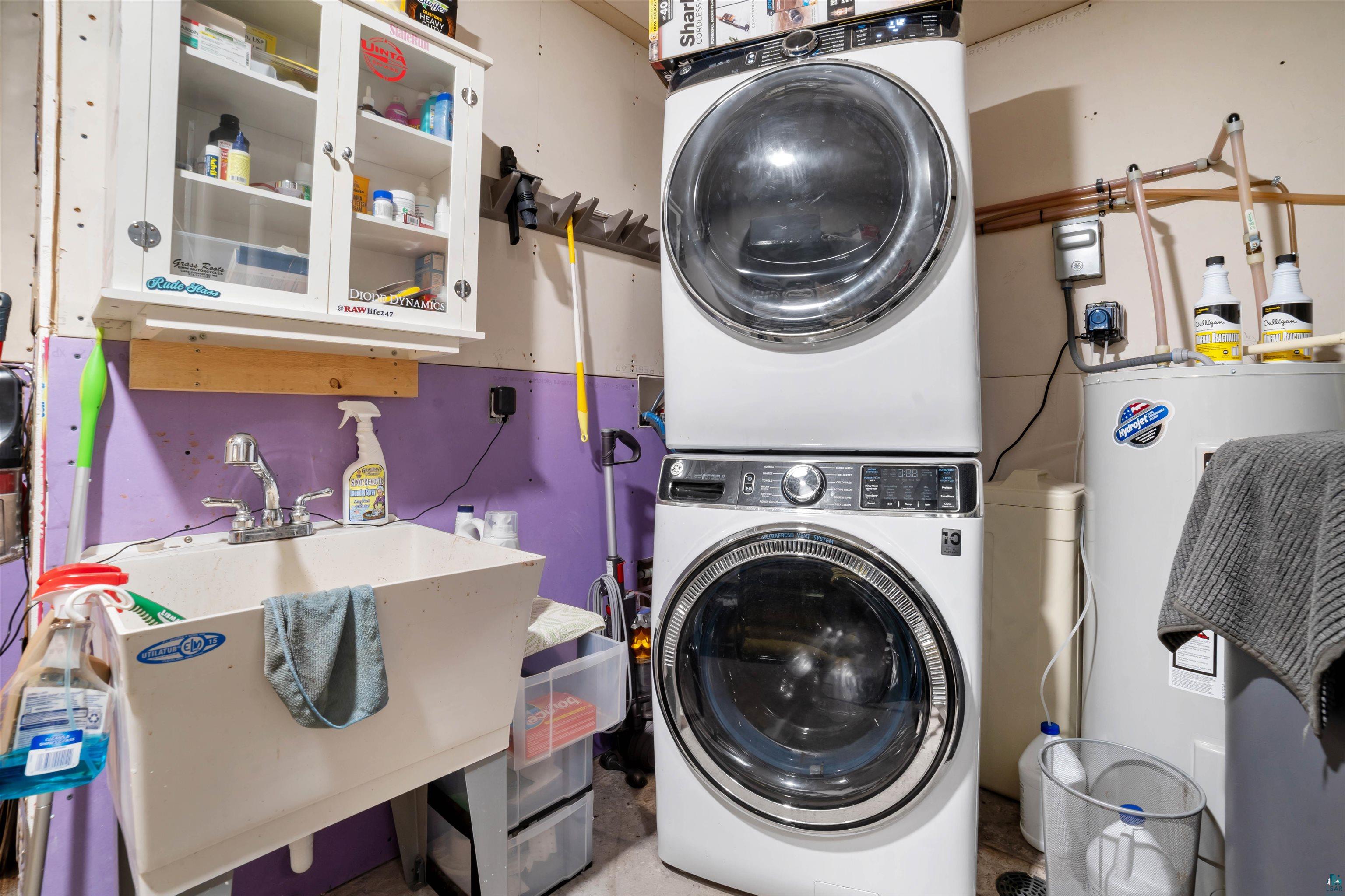 1159 East County Rd B Foxboro, WI 54836 - Photo 24 of 29 Clothes washing area with water heater, sink, and stacked washer and dryer