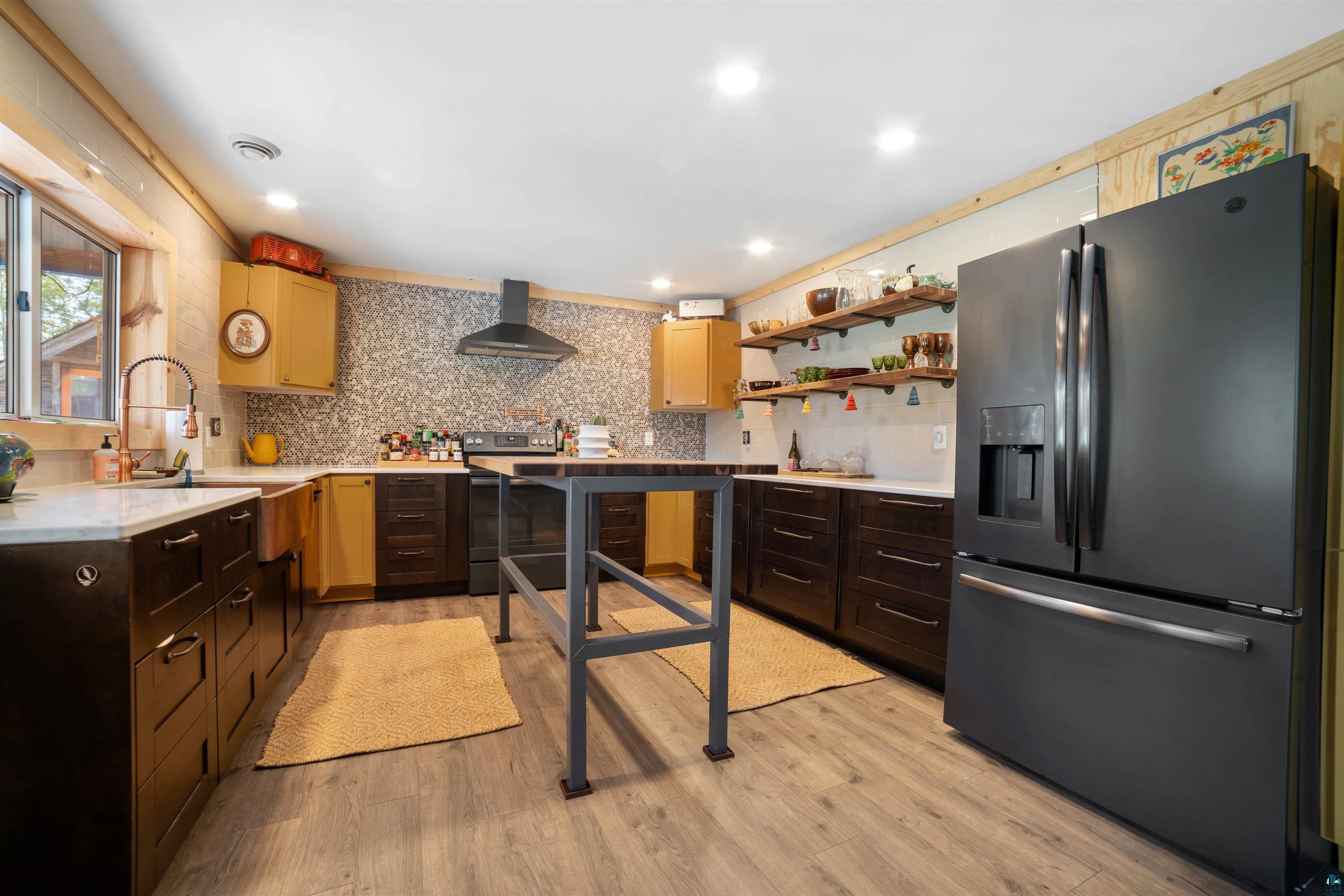 1159 East County Rd B Foxboro, WI 54836 - Photo 10 of 29 Kitchen with light hardwood / wood-style flooring, sink, decorative backsplash, appliances with stainless steel finishes, and wall chimney range hood
