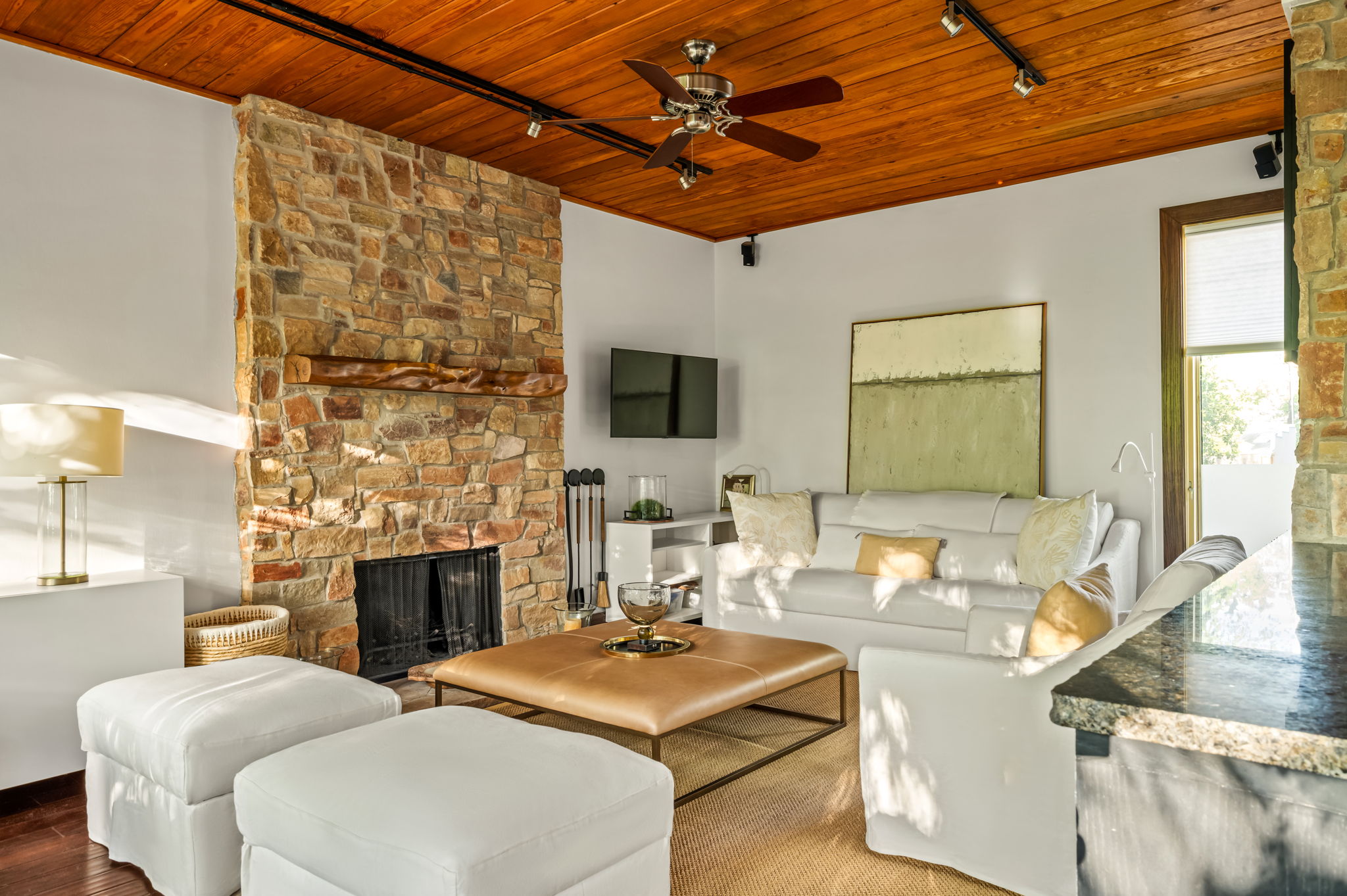 1111 West 12th Street, Unit 107 Austin, TX 78703 - Photo 15 of 38 Stone fireplace with a live-edge wood mantel, wood-plank ceiling, ceiling fan, track lighting, and a built-in granite-finish countertop