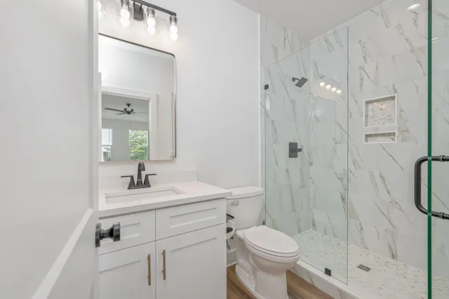 a bathroom with a granite countertop sink a mirror and shower