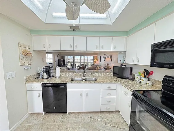 a kitchen with a sink dishwasher a stove a microwave oven and white cabinets