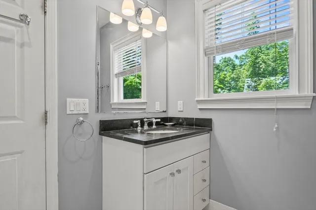 a bathroom with a granite countertop sink a large mirror and a window