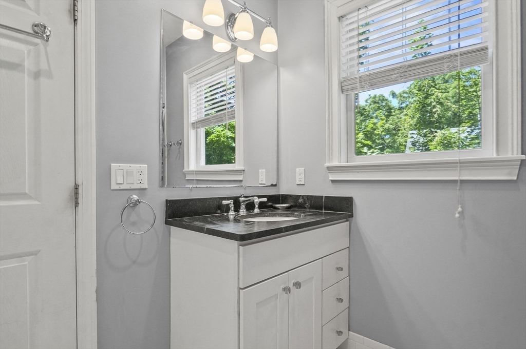 5 Waban Street Natick, MA 01760 - Photo 16 of 32 a bathroom with a granite countertop sink a large mirror and a window