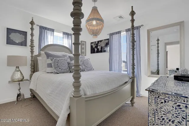 a bedroom with a bed a chandelier and dresser
