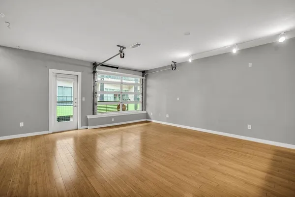 a view of an empty room with wooden floor and a window