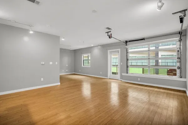 a view of an empty room with wooden floor and a window