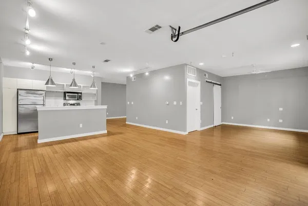 a view of kitchen and empty room with wooden floor