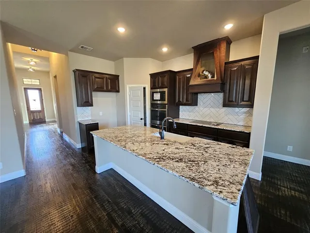 an empty room with wooden floor fireplace and windows