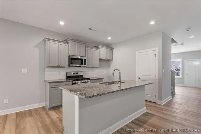 a kitchen with stainless steel appliances granite countertop a sink a stove a refrigerator and cabinets