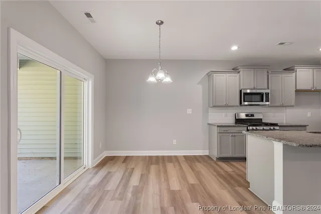 a kitchen with stainless steel appliances granite countertop a refrigerator a stove and a sink with wooden floor