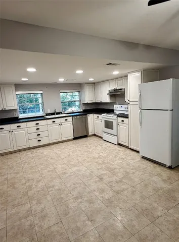 a large kitchen with granite countertop a stove top oven a sink a counter space and cabinets