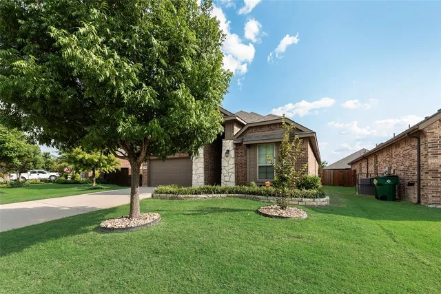 a front view of a house with garden and trees