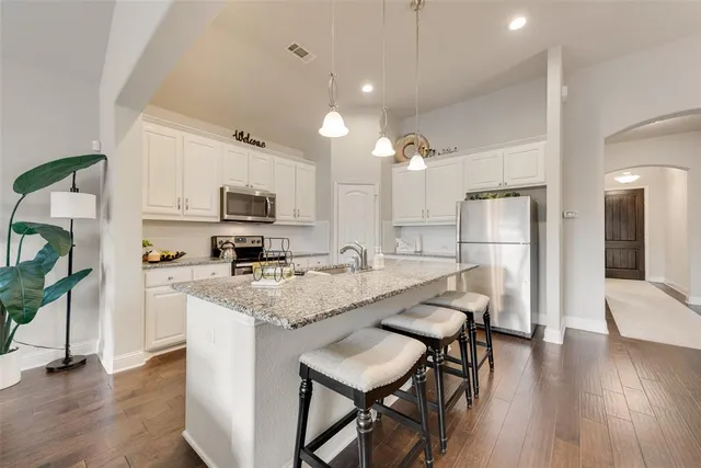 a kitchen with stainless steel appliances granite countertop a table chairs refrigerator and microwave