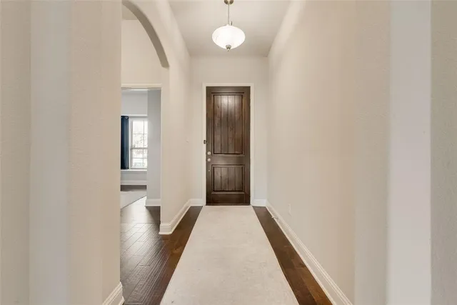a view of a hallway with wooden floor and a bathroom