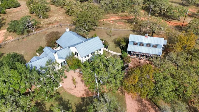 an aerial view of a house with a yard and trees all around