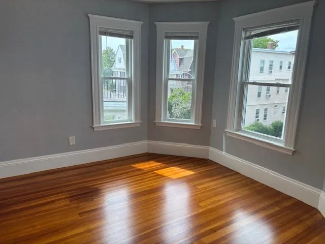 a view of an empty room with wooden floor and a window