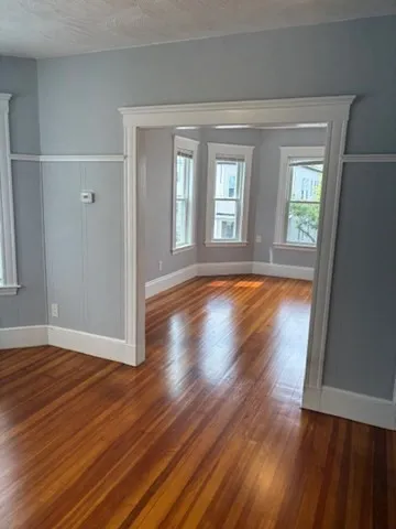 a view of empty room with wooden floor and fan
