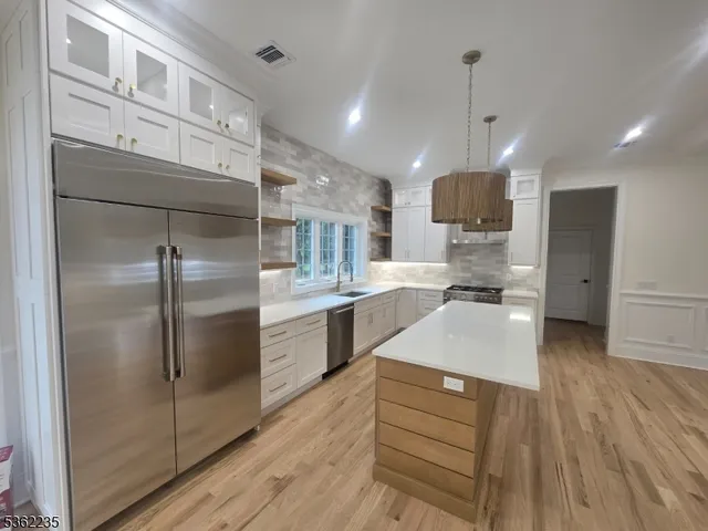 a large kitchen with kitchen island a sink stainless steel appliances and cabinets