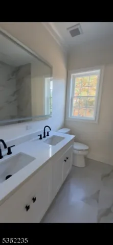 a bathroom with a double vanity sink toilet and a mirror