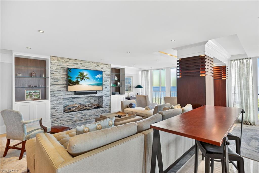 5601 Turtle Bay Drive, Unit 2104 Naples, FL 34108 - Photo 4 of 31 Living room with built in shelves, a stone fireplace, and recessed lighting