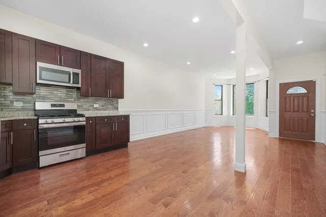 a large kitchen with stainless steel appliances granite countertop a stove a sink dishwasher and a microwave oven with wooden floor