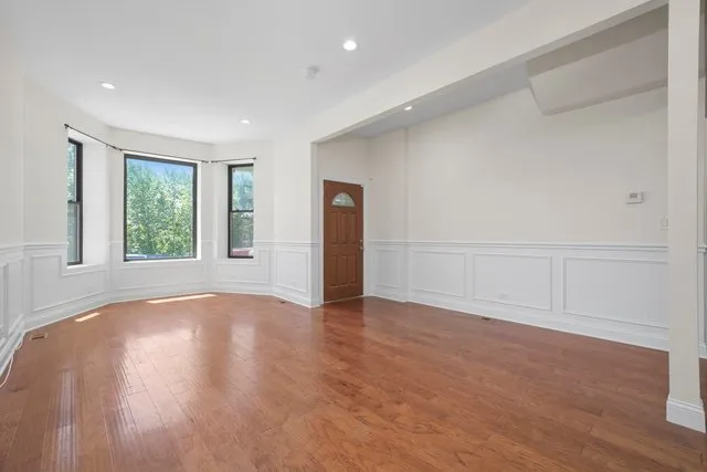 a view of an empty room with wooden floor and window