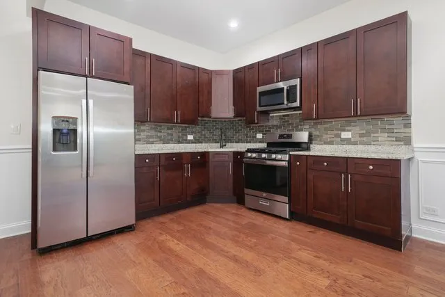 a kitchen with stainless steel appliances granite countertop a stove a refrigerator and a sink