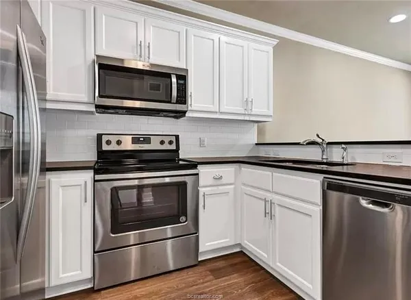 a kitchen with stainless steel appliances granite countertop a stove a microwave and a white cabinets