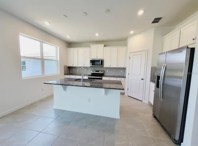 a kitchen with stainless steel appliances granite countertop a refrigerator a sink a stove a microwave a counter top and oven