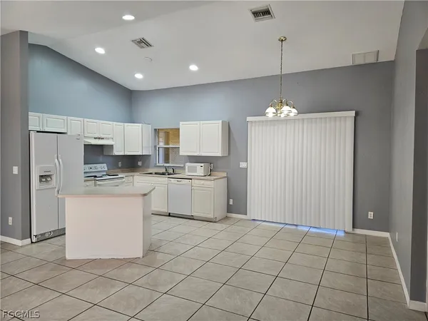 a kitchen with white cabinets a sink dishwasher and a stove with kitchen island