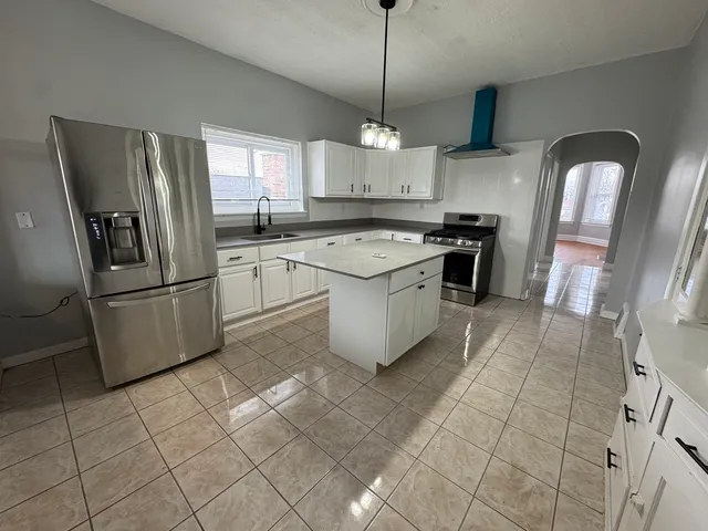 a kitchen with stainless steel appliances granite countertop a refrigerator a sink dishwasher a stove and white cabinets with wooden floor