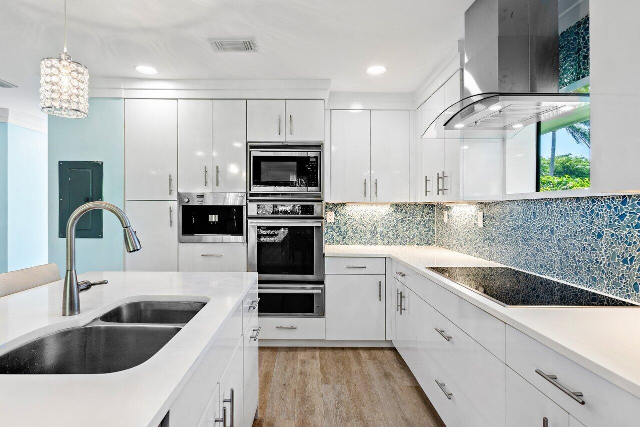 a kitchen with a sink dishwasher a stove and white cabinets with wooden floor