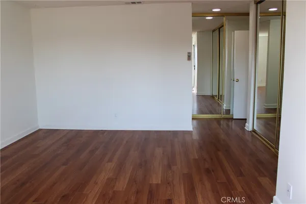 a view of a hallway with wooden floor and a bathroom