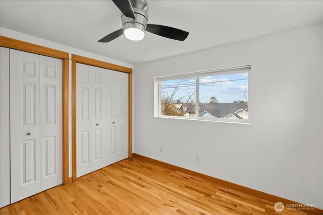 a view of empty room with wooden floor and fan