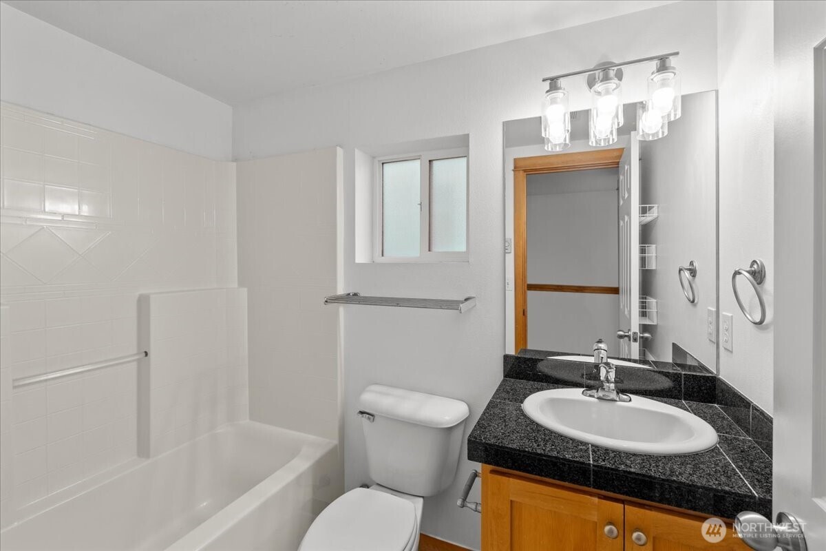 6348 34th Avenue Southwest, Unit C Seattle, WA 98126 - Photo 22 of 26 a bathroom with a granite countertop sink toilet and mirror