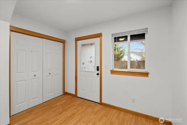a view of an empty room with wooden floor and a window