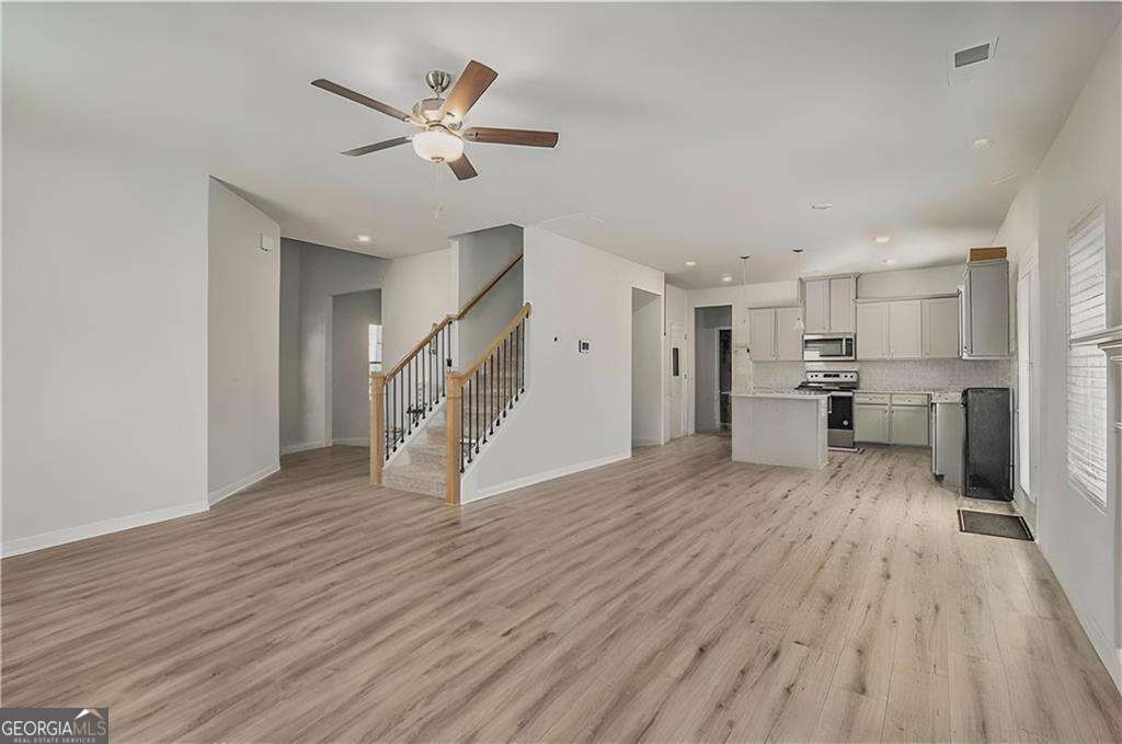 1101 Longleaf Trace Monroe, GA 30656 - Photo 12 of 36 a view of an empty room with wooden floor and a ceiling fan
