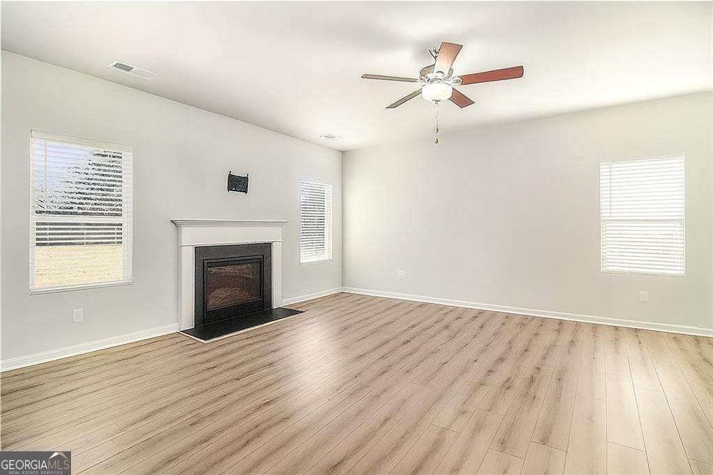 1101 Longleaf Trace Monroe, GA 30656 - Photo 9 of 36 an empty room with wooden floor a fireplace and windows