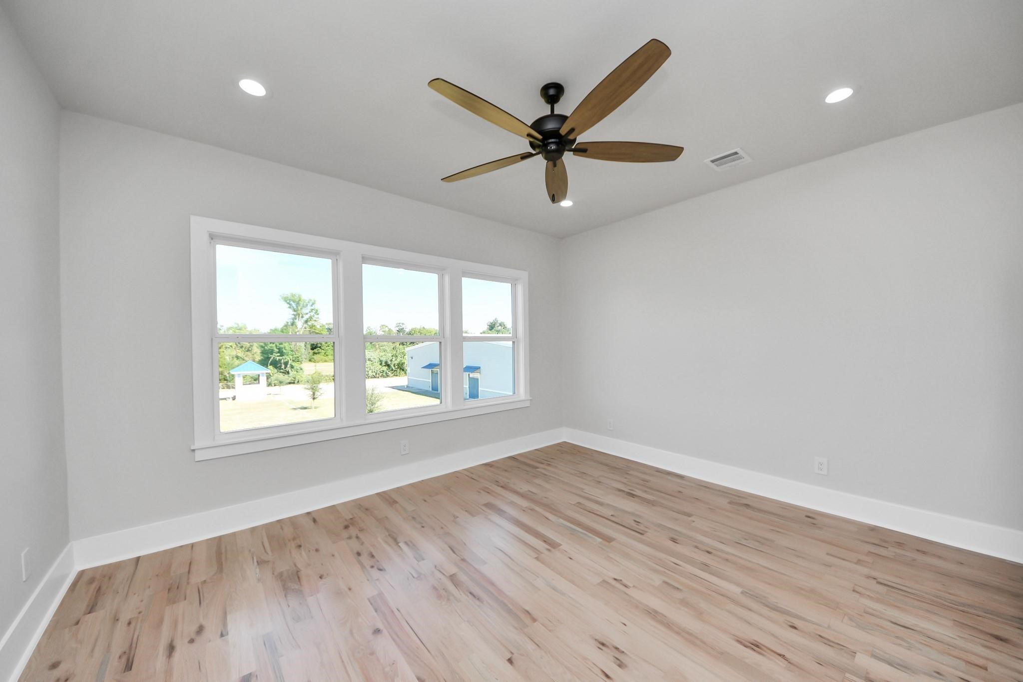 6320 Milwee Street, Unit B Houston, TX 77092 - Photo 17 of 30 an empty room with wooden floor fan and windows