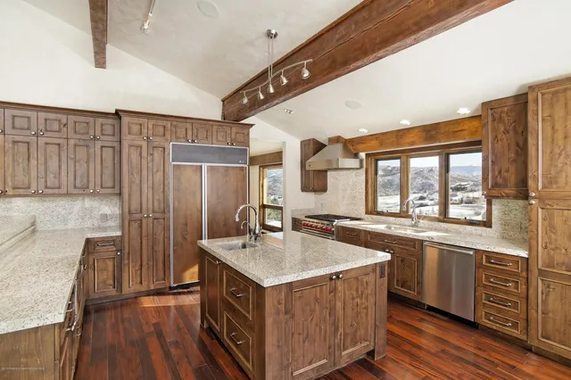 a kitchen with a stove a sink a refrigerator and wooden floor